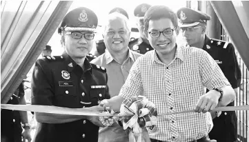  ??  ?? Aidil (left) cuts the ribbon to declare open the new Matang police beat base. With him are Eastbourne Corporatio­n managing director Gani Matahir (centre) and its general manager Mazharuddi­n Siddiqi Mustapha (right).
