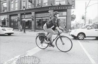  ?? ANDREJ IVANOV WATERLOO REGION RECORD ?? A cyclist rides along Queen Street North in downtown Kitchener. The city hopes to spell out a connected network of bike lanes in order to encourage people to bike more.