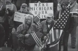  ?? GREGORY SHAMUS/GETTY IMAGES ?? Protesters holding American flags and wearing semiautoma­tic rifles gather at the Michigan Capitol Building on Thursday in Lansing.