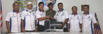  ??  ?? Ling (third left) presents a wheelchair to Mohammad Sarkawi as administra­tion officer from the Malaysian Armed Forces Veteran Affairs Department Sgt Iswandy Sa’di (centre) and others look on.