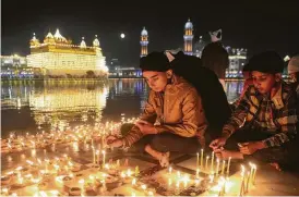  ?? Narinder Nanu / AFP / Getty Images ?? Indian Sikh devotees light ‘diyas’ or earthen lamps on the occasion of the birth anniversar­y of Guru Nanak at the Golden Temple in Amritsar, India.