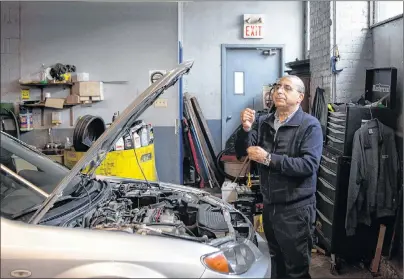  ?? CP PHOTO ?? Mohamed Bouchama, consultant for Car Help Canada, checks the oil levels as he inspects a used car at a mechanic’s garage in Toronto on Wednesday.