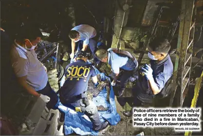  ?? MIGUEL DE GUZMAN ?? Police officers retrieve the body of one of nine members of a family who died in a fire in Maricaban, Pasay City before dawn yesterday.