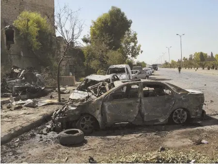  ?? AP PHOTO ?? DEADLY EXPLOSION: Several damaged cars are seen along the road to the airport in southeast Damascus yesterday after a suicide car blast that killed at least eight people.