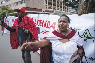  ?? ?? National coordinato­r of the Maa Unity Agenda group Jonathan Mpute ole Pasha (left) and other Maasai rights activists march Friday towards the Tanzanian high commission in downtown Nairobi, Kenya.