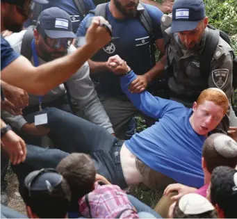  ?? Photo: AP/Ariel Schalit ?? Israeli police evict Jewish settlers at the West Bank settlement of Netiv Ha’avot yesterday after Israel’s Supreme Court ordered the eviction.