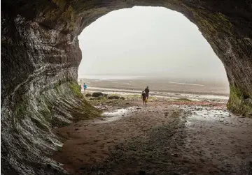  ??  ?? Tourists explore the St. Martins sea caves at low tide, a short trip from the western Fundy Trail Parkway.