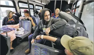  ?? Gary Coronado Los Angeles Times ?? SEAN KNUDSEN, center, and other homeless people are bused Feb. 19 from a Santa Ana River encampment to an Anaheim motel. Orange County cities have opposed plans to shelter hundreds of the relocated people.