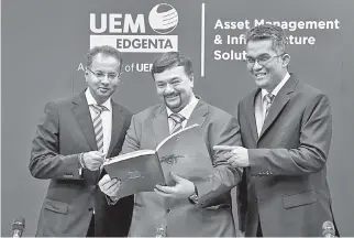  ?? — Bernama photo ?? UEM Edgenta chairman Amir Hamzah Azizan (middle) looks on at UEM Edgenta’s Annual Report 2018 during the group’s AGM yesterday. Also present are Azmir (left) and chief financial officer Muhammad Noor Abd Aziz.