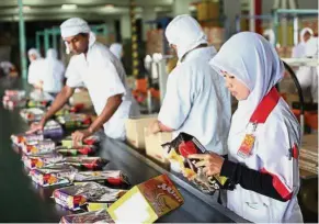  ??  ?? Keen interest: Workers manning a production line at a Munchy’s factory. Red Sena is reportedly eyeing Retirement Fund Inc’s stake in the confection­ery product manufactur­er.