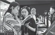  ?? LIANG XU / XINHUA ?? A visitor ( left) learns about wireless earphones at the 2019 China Hi- Tech Fair in Shenzhen, Guangdong province, in November.