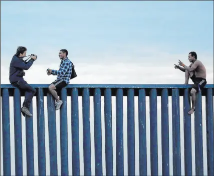  ?? Gregory Bull The Associated Press ?? Men pose in November 2018 after climbing the border wall separating Tijuana, Mexico, and San Diego.