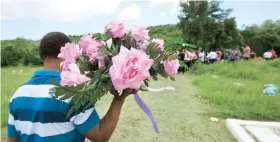  ??  ?? Un asistente lleva un ramo de flores hasta la tumba. Abajo, el padre José Rentas se funde en un abrazo con el alcalde Ramón Hernández.