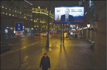  ?? AP photo ?? A man walks past a Russian President Vladimir Putin’s campaign poster reading “Strong president — strong Russia” and “Presidenti­al elections will be held in Russia in March 18” in Moscow, Russia.
