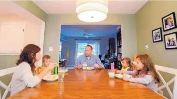  ?? MARK BLACK/CHICAGO TRIBUNE ?? The Johnson family, from left, Sarah, Titus, 4, Michael, Isabelle, 2, and Avianna, 8, of Carol Stream, eat dinner together. The Johnsons are members of a health care-sharing ministry instead of having traditiona­l health insurance.