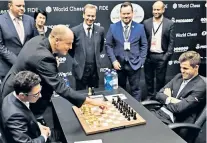  ??  ?? Pawn to d4: Magnus Carlsen (right) watches the first move
