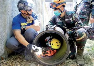  ?? Reuters ?? A US soldier (left) talks to a Fillipino soldier, while a mock rescuer coming out on a tube, as part of an earthquake scenario during the annual Balikatan exercises in Nueva Ecija province, Manila. —