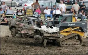  ?? JONATHAN TRESSLER — THE NEWS-HERALD ?? A member of the Demolition Derby clean-up crew uses a skid-steer loader equipped with a fork to remove one of the B-Feature 4-man Team cars, driver and all, from the mud pit where it all goes down, before the next demo-derby event takes place July 29 during the final hours of the 2018 Lake County Fair.