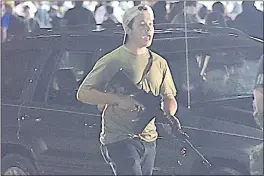  ?? ADAM ROGAN — THE JOURNAL TIMES ?? Kyle Rittenhous­e carries a weapon as he walks along Sheridan Road in Kenosha, Wis., during a night of unrest following the weekend police shooting of Jacob Blake.