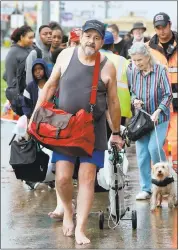  ?? MELISSA PHILLIP — HOUSTON CHRONICLE ?? Houston residents straggle along the path to board buses to be taken to a shelter on Sunday.