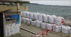  ?? (Photo Eric Ottino) ?? Une barrière de sacs de sable a été installée pour protéger le bâtiment qui doit abriter la nouvelle base nautique.