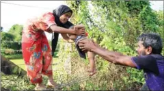  ?? REHMAN ASAD/AFP ?? A Rohingya man passes a child through a barbed wire border fence near Maungdaw on the border with Bangladesh on Monday.