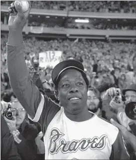  ?? THE ASSOCIATED PRESS ?? In this April 8, 1974, file photo, Hank Aaron holds aloft the ball he hit for his 715th career home run in Atlanta.