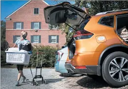  ?? JULIAWALL/THE NEWS & OBSERVER ?? Darlene Genander helps a student move out of her dormWednes­day at the University of North Carolina at Chapel Hill. The college halted in-person classes last week.