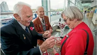  ?? PHOTO: MURRAY WILSON/ FAIRFAX NZ ?? Collector Pat Hickton looks on as Maurice Collins places a poppy on Heather Greig.