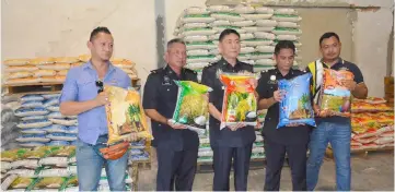  ??  ?? Tan (centre) and his men show the repacked rice found at the warehouse.
