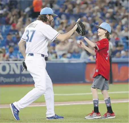  ?? TOM SZCZERBOWS­KI/GETTY IMAGES ?? Reliever Jason Grilli of the Toronto Blue Jays high-fives his son Jayse Grilli after catching the ceremonial first pitch before the start of Sunday’s Father’s Day game against the Chicago White Sox at Rogers Centre. The Jays were 7-3 winners.