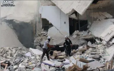  ?? ALEPPO MEDIA CENTER VIA AP ?? This photo provided by the Syrian anti-government activist group Aleppo Media Center shows Syrian civil defense workers inspecting damaged buildings, after barrel bombs were dropped on the Bab al-Nairab neighborho­od in Aleppo, Syria, on Saturday. Syria...