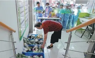  ?? YIN LIQIN / CHINA NEW SERVICE ?? Workers wait for free vegetables at a food bank in Shanghai.