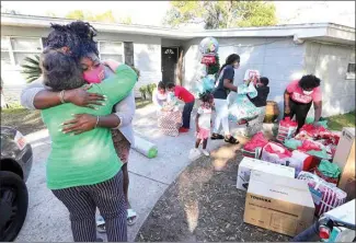  ?? JOE BURBANK / ORLANDO SENTINEL VIA AP ?? Valon Jackson, whose mother and aunt died of COVID-19 complicati­ons in August, gets a hug from Angie Black of the Coalition for the Homeless of Central Florida, left, during a surprise delivery of Christmas gifts to Jackson’s new home Dec. 22.
