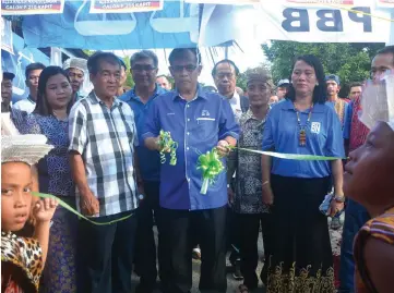  ??  ?? Jamit cuts the ribbon to officiate the opening of the Tatai Panglima housing estate. At his right is Abang Hamzah and on his left is Gupie.