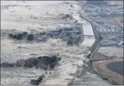  ?? THE ASSOCIATED PRESS ?? An earthquake-triggered tsunami sweeps ashore along Iwanuma, Miyagi prefecture in northern Japan on March 11, 2011. At least 18,000 people were killed.