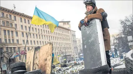  ?? Picture: Getty Images. ?? An anti-government protester stands on top of a barricade as a Ukrainian flag waves in central Kiev.