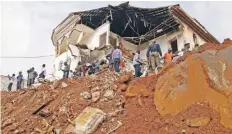  ??  ?? Lugareños se reúnen frente a un edificio dañado por un alud en Freetown, que dejó cientos de muertos. El gobierno declaró siete días de luto.