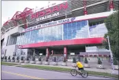  ?? MARK HUMPHREY — THE ASSOCIATED PRESS ?? A cyclist passes by Nissan Stadium, home of the Titans, on Tuesday in Nashville, Tenn. The Titans suspended inperson activities through Friday after the NFL says three Titans players and five personnel tested positive for the coronaviru­s.