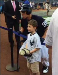  ?? BEN WALKER — THE ASSOCIATED PRESS ?? In this photo taken Friday, New York Yankees crowd favorite Aaron Judge crouches to pose for a photo with a young fan before playing the Baltimore Orioles in a baseball game in New York.