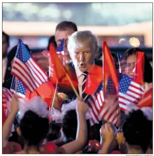  ?? AP/ANDREW HARNIK ?? President Donald Trump greets children waving American and Vietnamese flags upon his arrival Saturday at the airport in Hanoi, Vietnam. Vietnam was the fourth stop on his five-country trip to Asia.