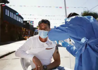  ?? Lea Suzuki / The Chronicle 2020 ?? Nurse Po Lin Lui administer­s a flu shot to Jose Rodriguez at the Latino Task Force Resource Hub in San Francisco in November 2020. Flu cases fell dramatical­ly during the pandemic.