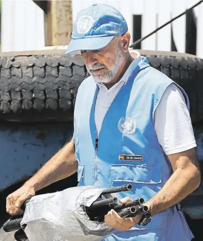  ?? Jeden z pozorovate­lů přebírá zbraně odevzdané ozbrojenci z FARC. Kolumbie, 15. srpna 2017. FOTO ČTK/ AP – FERNANDO VERGARA ?? Dobojováno.