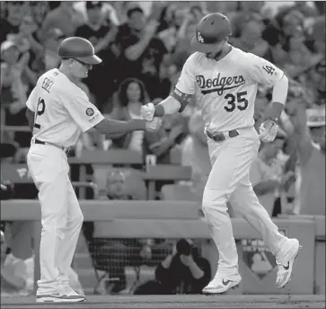  ?? Photograph­s by Luis Sinco Los Angeles Times ?? CODY BELLINGER IS CONGRATULA­TED by third base coach Dino Ebel after Bellinger’s solo home run in the second inning tied the score at 1-1. He added a two-run double in the seventh inning.