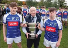  ??  ?? Éire Óg’s joint captains Daire Devine and Fionn O’Carroll receive the cup from Coiste na nÓg chairman Pat Dunne.
