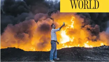  ?? YASIN AKGUL / AFP / GETTY IMAGES ?? A man takes a photo in the Qayyarah area south of Mosul on Wednesday during an operation by Iraqi forces against ISIL.