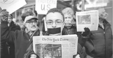  ??  ?? A man covers his mouth with tape as he takes part in a protest outside the New York Times in New York. — AFP photo