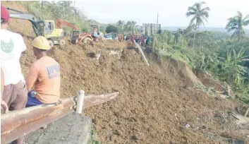  ?? — AFP ?? Bulldozers work on the edge of a collapsed highway after typhoon Kai-Tak in Pinabacdao town, western Samar province, on Sunday.