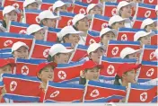  ?? LEE JIN-MAN/ASSOCIATED PRESS FILE PHOTO ?? North Korean women hold national flags to cheer at the Daegu Universiad­e Games in 2003 in Daegu, South Korea.