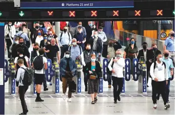  ?? AP ?? People wear face masks to curb the spread of coronaviru­s during the morning rush hour at Waterloo train station in London on Wednesday.